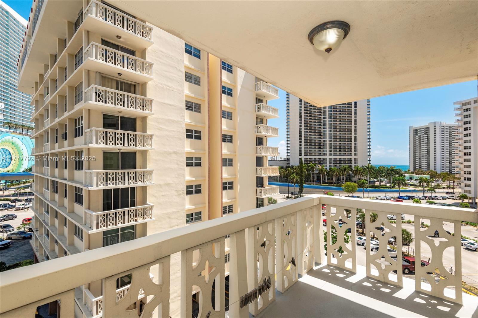 A balcony with decorative railings overlooks a parking lot and surrounding high-rise buildings — 1817 S Ocean Dr # 628, Hallandale Beach FL 33009, HALLANDALE BEACH, FL
