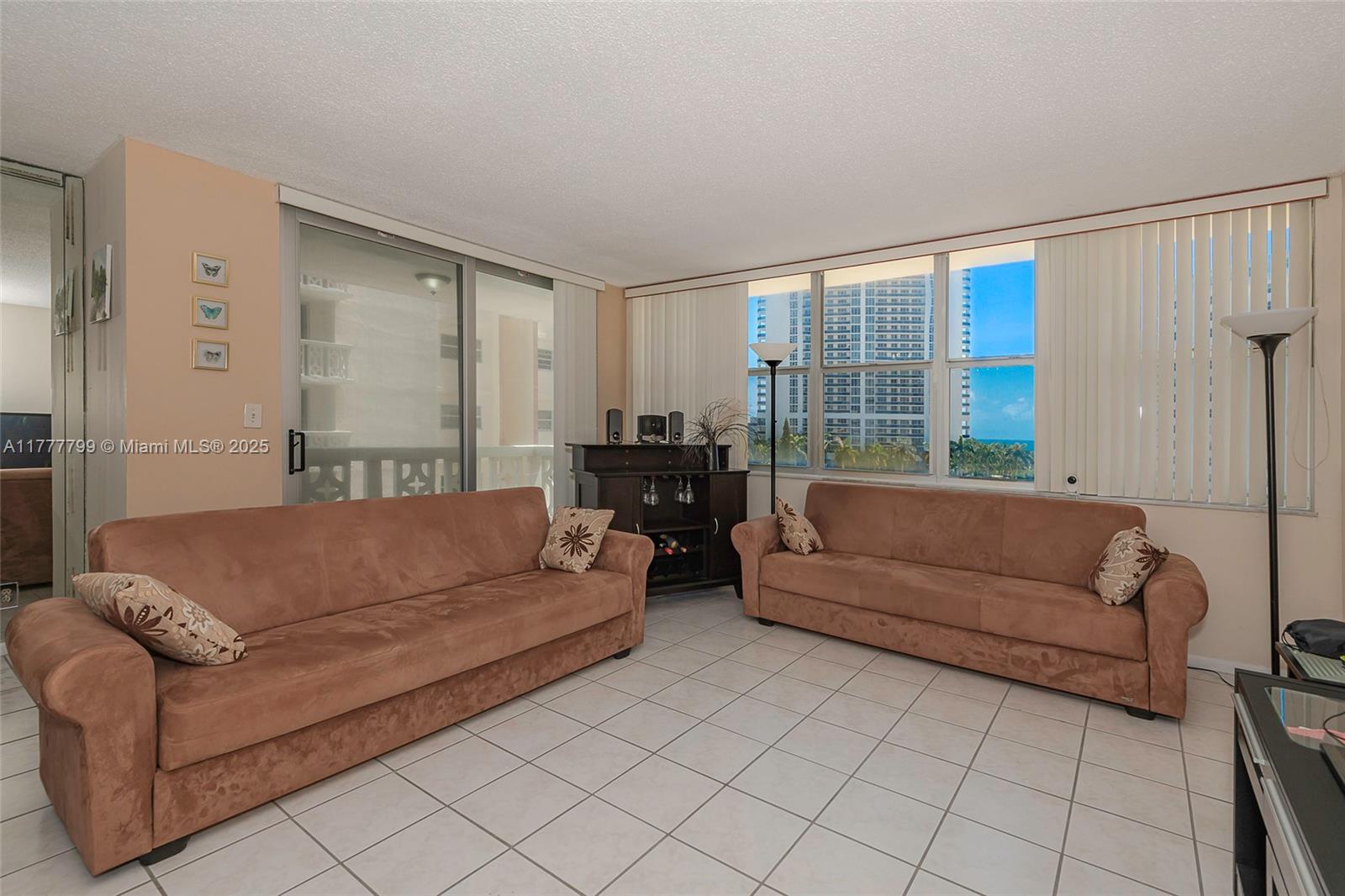 A living room features two brown sofas, tile flooring, and large windows with ocean views — 1817 S Ocean Dr # 628, Hallandale Beach FL 33009, HALLANDALE BEACH, FL
