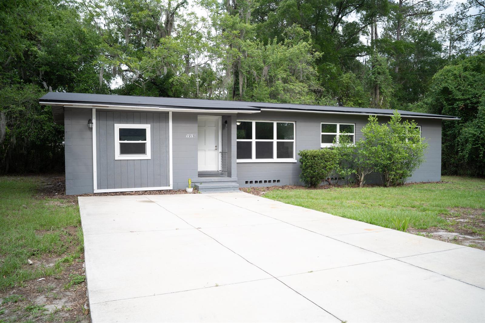 A gray, single-story house with a white front door and a concrete driveway — 1015 SE 10th Terrace, Gainesville FL 32601, GAINESVILLE, FL