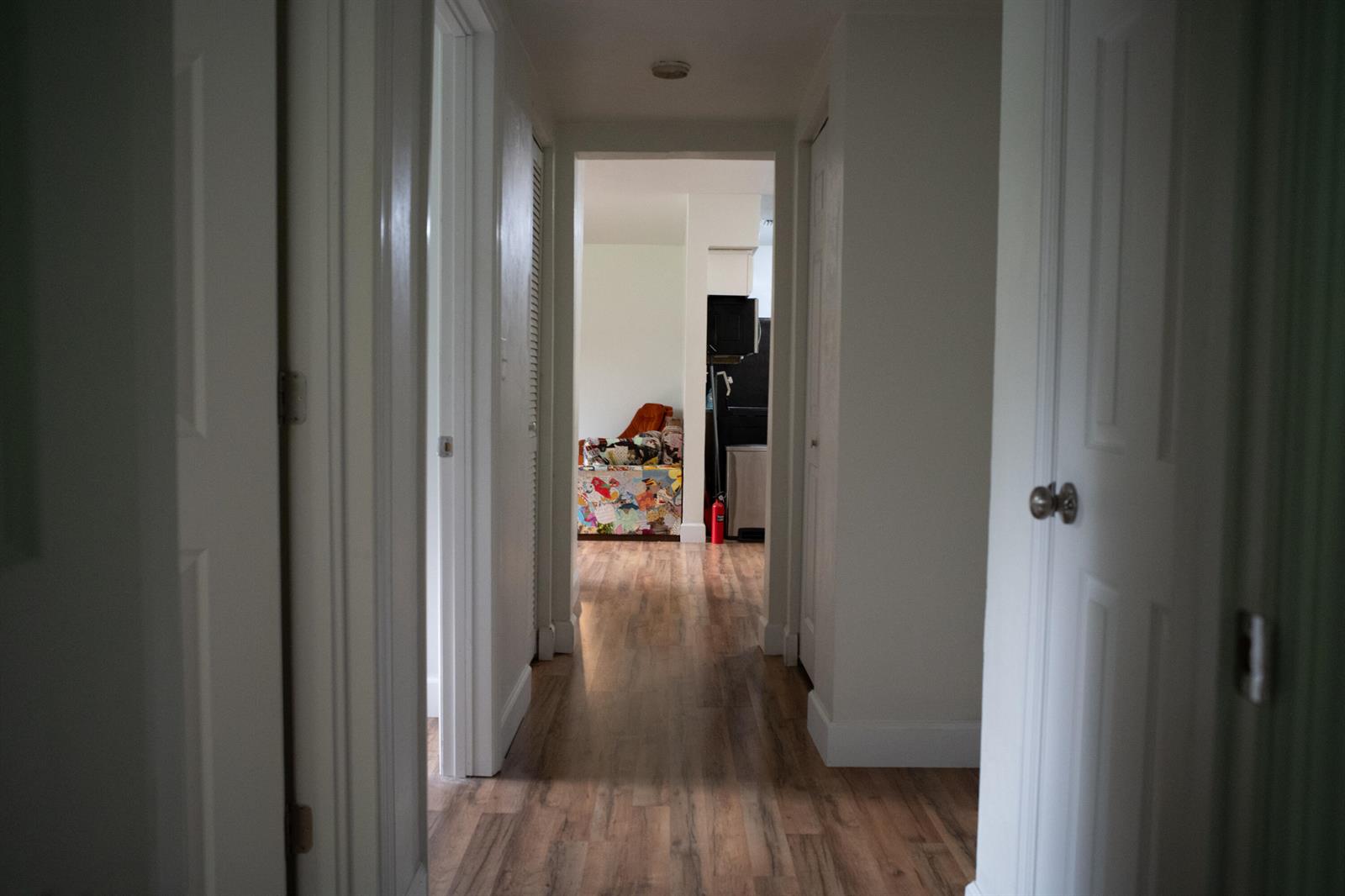 A hallway with wood-look flooring leads to a room with a colorful patterned piece of furniture — 1015 SE 10th Terrace, Gainesville FL 32601, GAINESVILLE, FL