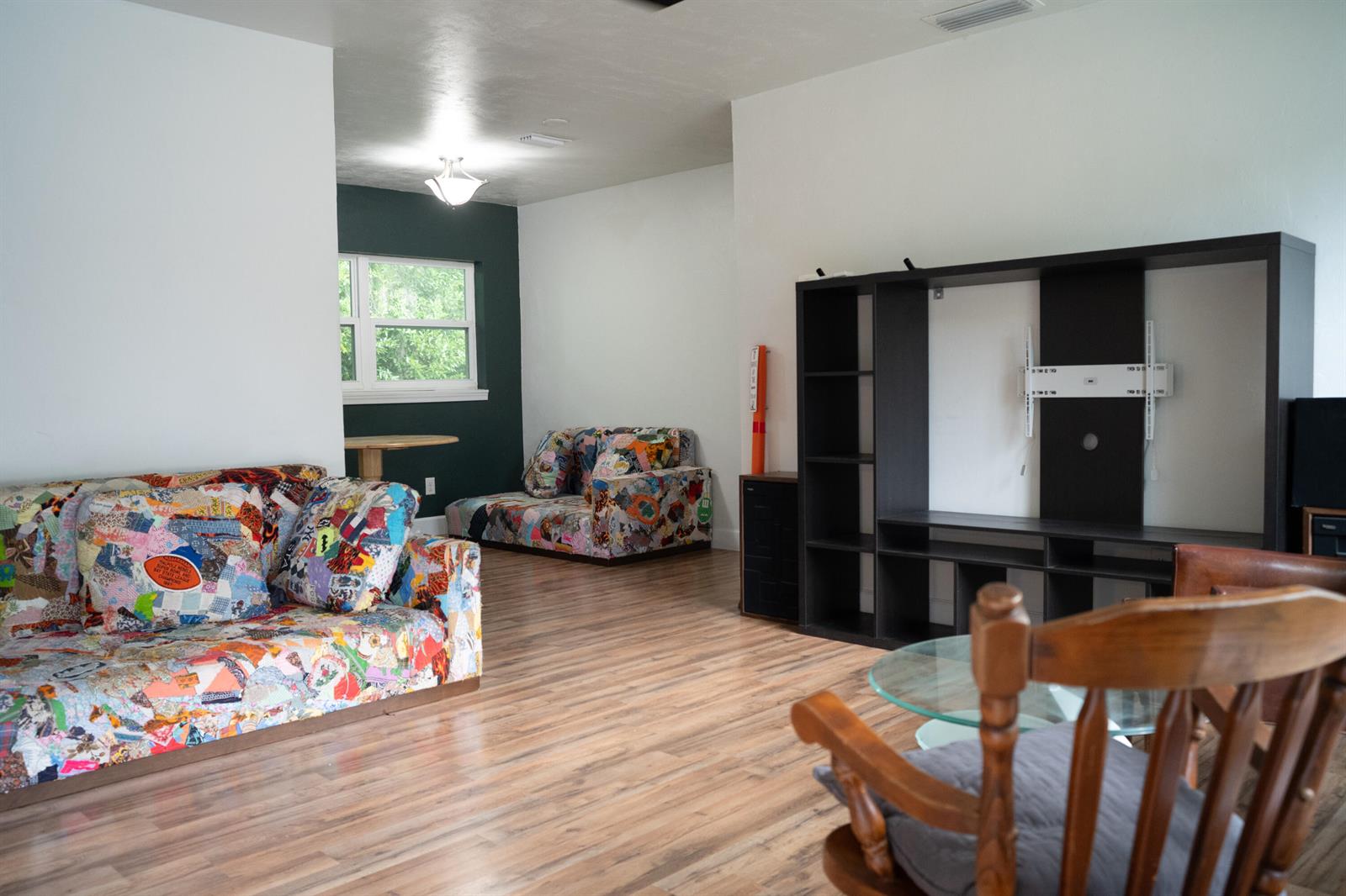 A living room features wood-look flooring, two patterned couches, and a large black media unit — 1015 SE 10th Terrace, Gainesville FL 32601, GAINESVILLE, FL