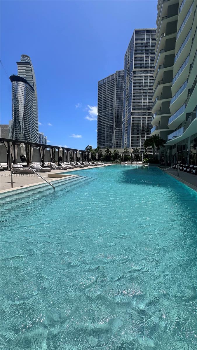A swimming pool sits on a terrace surrounded by modern high-rise apartment buildings — 77 SE 5th Street # 1915, Miami FL 33131, MIAMI, FL