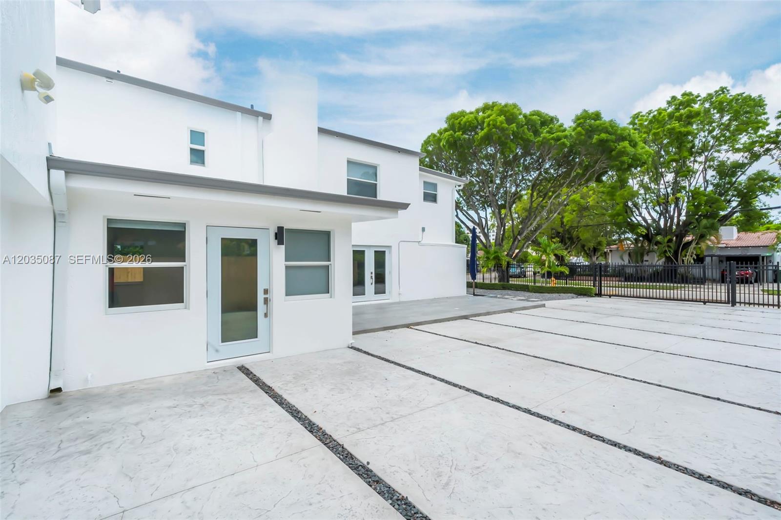 A white two-story house features a concrete driveway with gravel strips and a patio area — 590 SW 23rd Ave, Miami FL 33135, MIAMI, FL