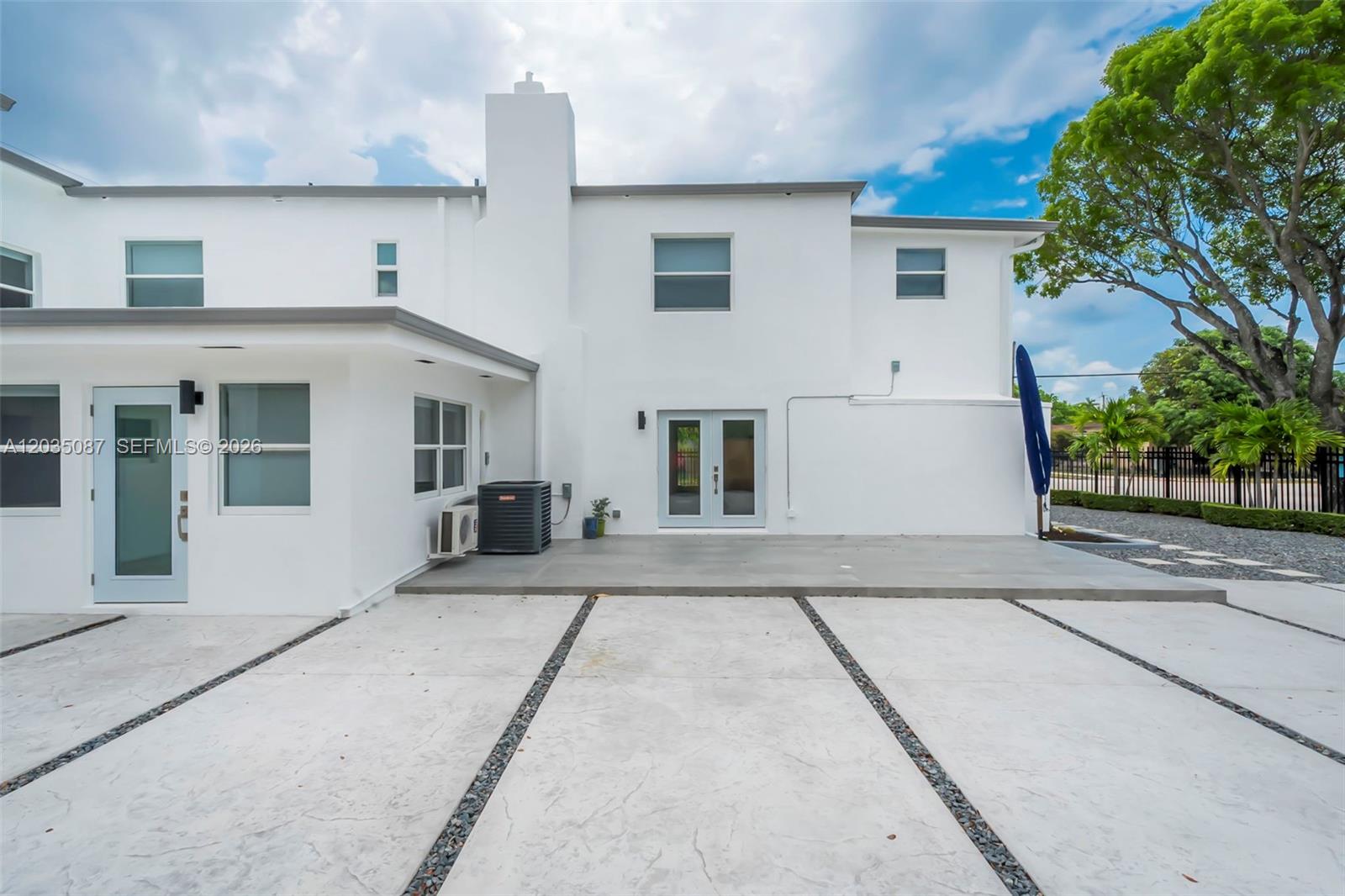 A white two-story house features a concrete patio and a driveway with gravel strips — 590 SW 23rd Ave, Miami FL 33135, MIAMI, FL
