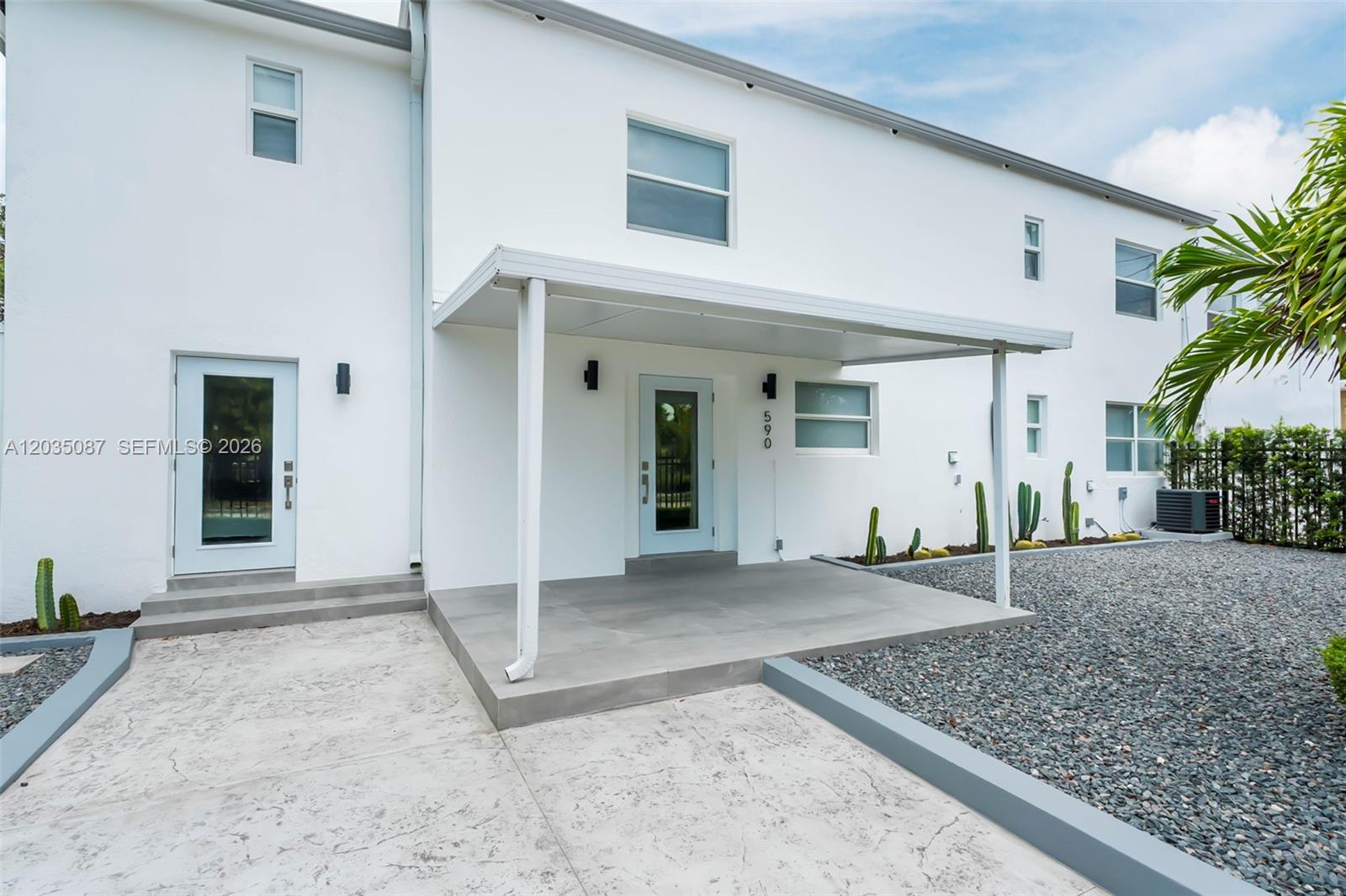 The exterior of a white two-story building features a covered patio and concrete driveway — 590 SW 23rd Ave, Miami FL 33135, MIAMI, FL
