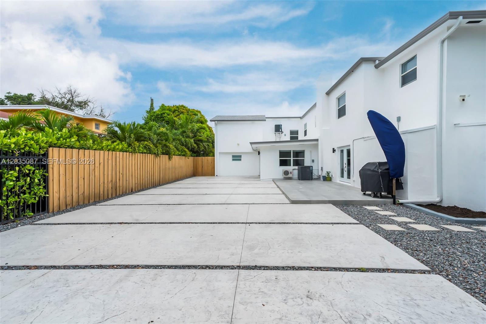 A paved driveway leads to the rear of a white two-story house with a fence — 590 SW 23rd Ave, Miami FL 33135, MIAMI, FL