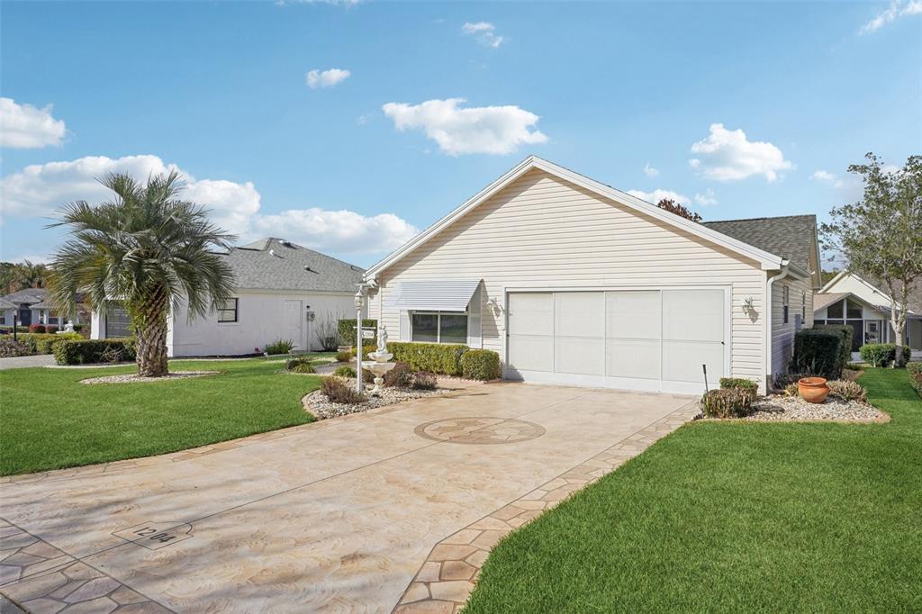 A single-story house with a beige vinyl exterior, a two-car garage, and a stamped concrete driveway — 1204 BARCELONA DRIVE, THE VILLAGES, FL