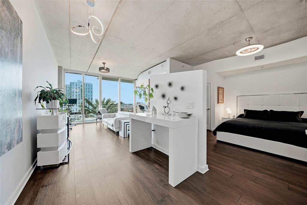 A modern studio apartment features a concrete ceiling, wood flooring, and a white room divider — 777 N ASHLEY DRIVE UNIT 1109, TAMPA, FL