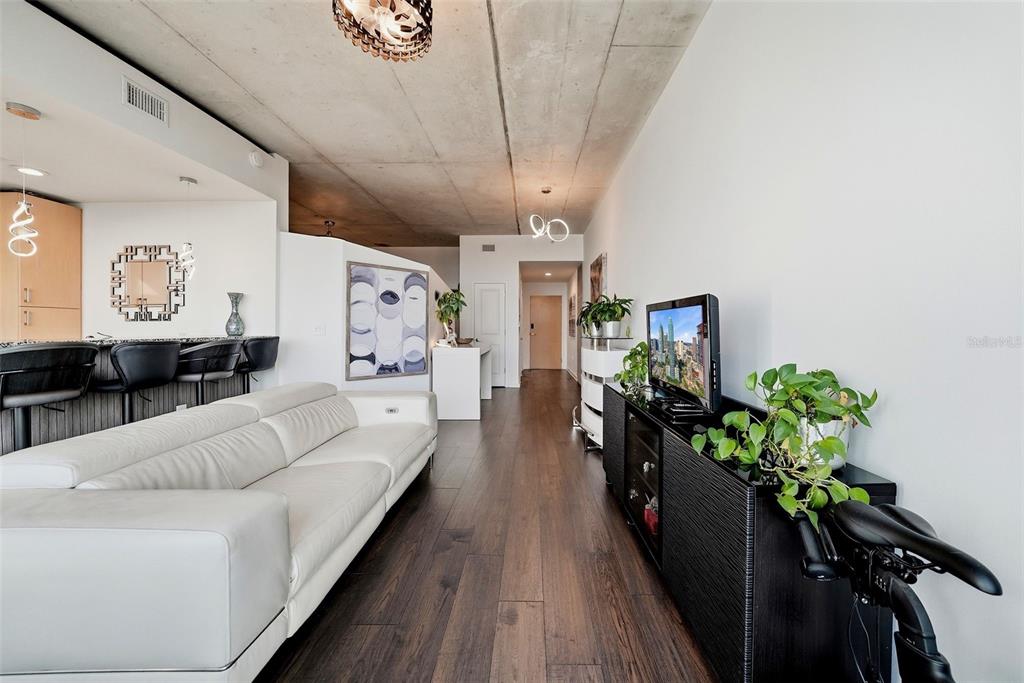 A modern living room features a white sofa, dark wood flooring, and an exposed concrete ceiling — 777 N ASHLEY DRIVE UNIT 1109, TAMPA, FL