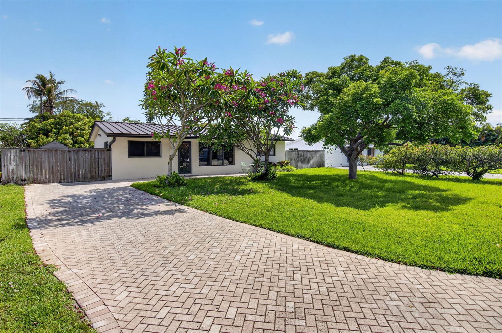 A single-story house with a paved driveway, a large lawn, and flowering trees — 115 NW 7th Street, Boca Raton FL 33432, BOCA RATON, FL