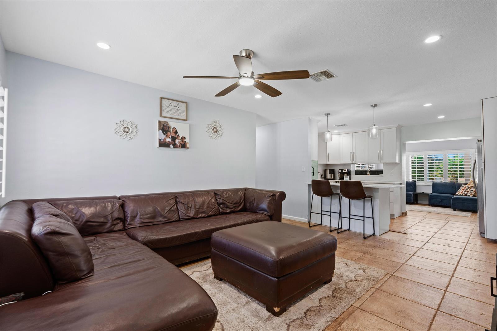 A living room with a brown leather sectional and ottoman opens to a white kitchen — 520 SE Dolphin Drive, Stuart FL 34996, STUART, FL