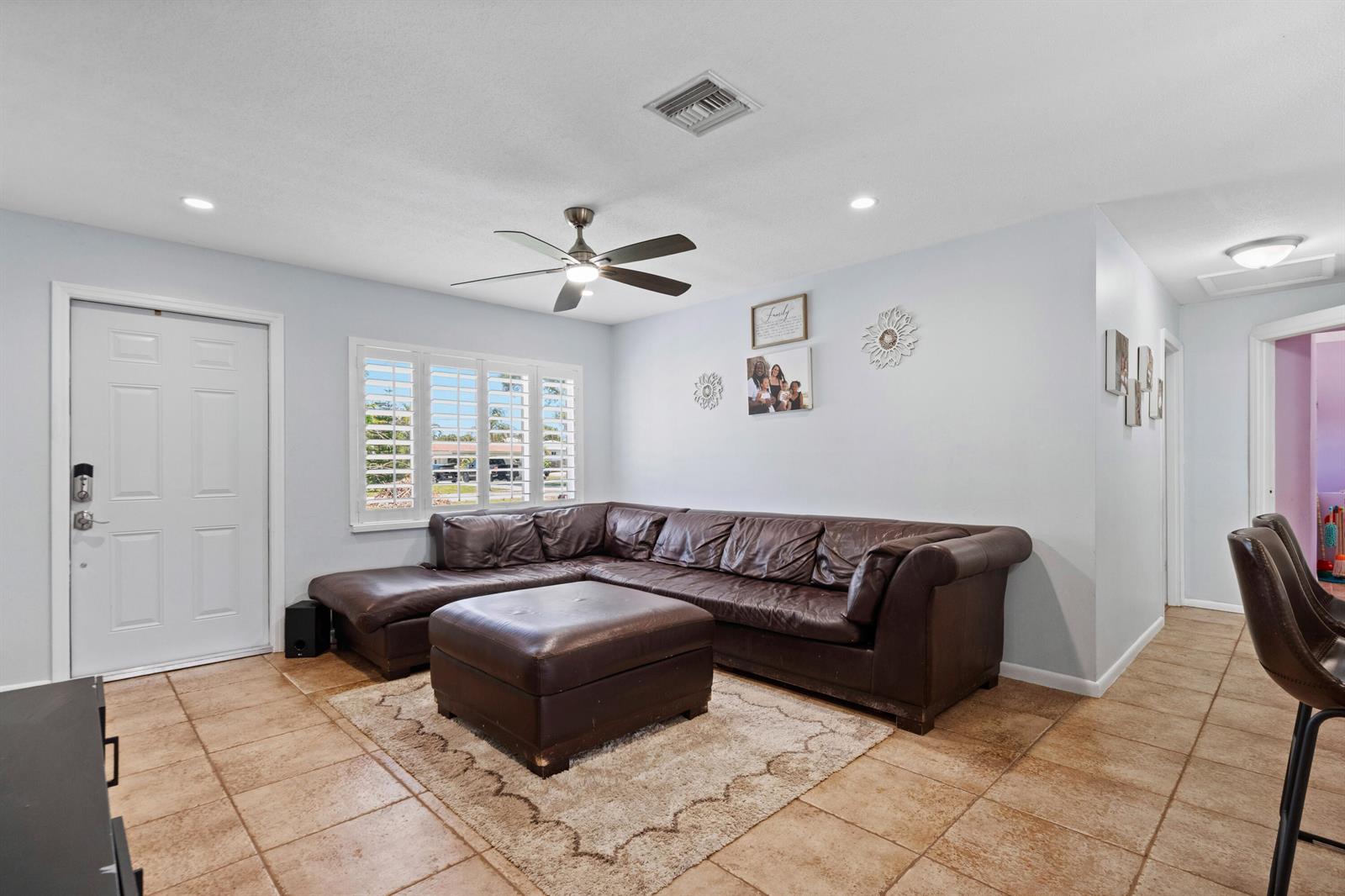 A living room features a brown leather sectional, a matching ottoman, and tile flooring — 520 SE Dolphin Drive, Stuart FL 34996, STUART, FL