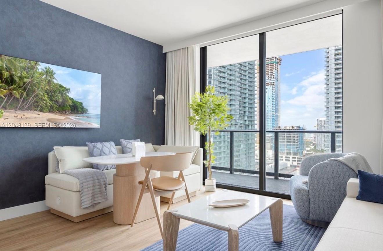 A living room features a blue accent wall, a dining nook, and floor-to-ceiling windows — 159 NE 6th St # 2002, Miami FL 33132, MIAMI, FL