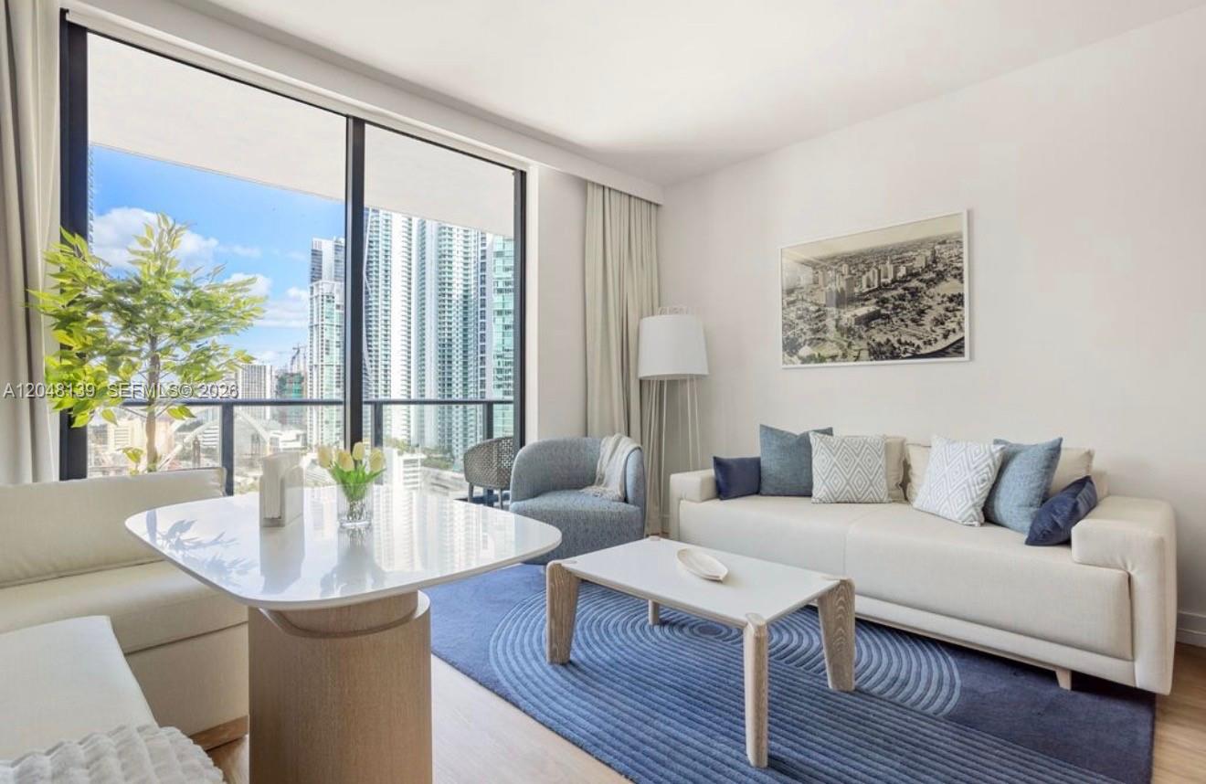 A living room features a white sofa, a blue area rug, and floor-to-ceiling windows — 159 NE 6th St # 2002, Miami FL 33132, MIAMI, FL