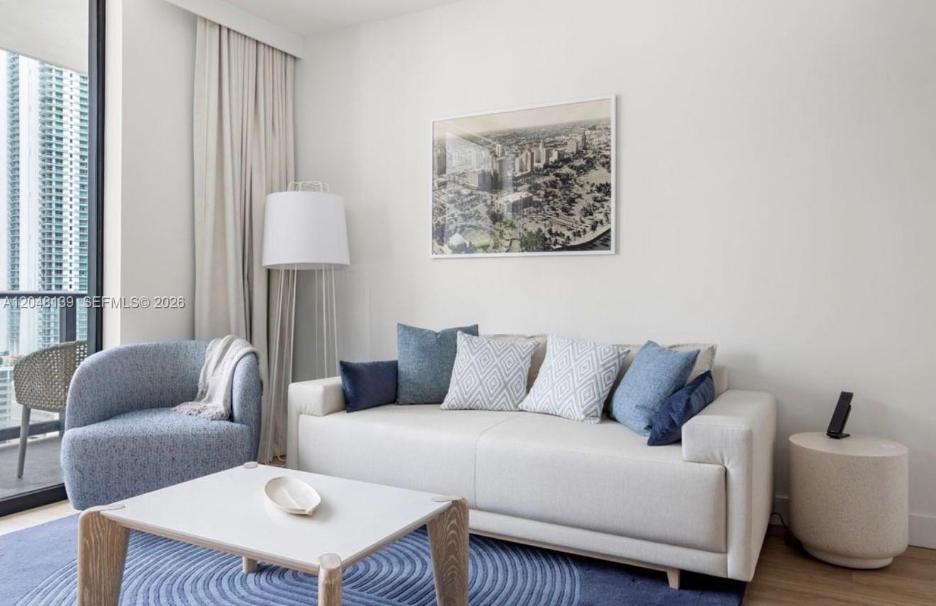 A modern living room features a white sofa, blue accent chair, and a city skyline print — 159 NE 6th St # 2002, Miami FL 33132, MIAMI, FL