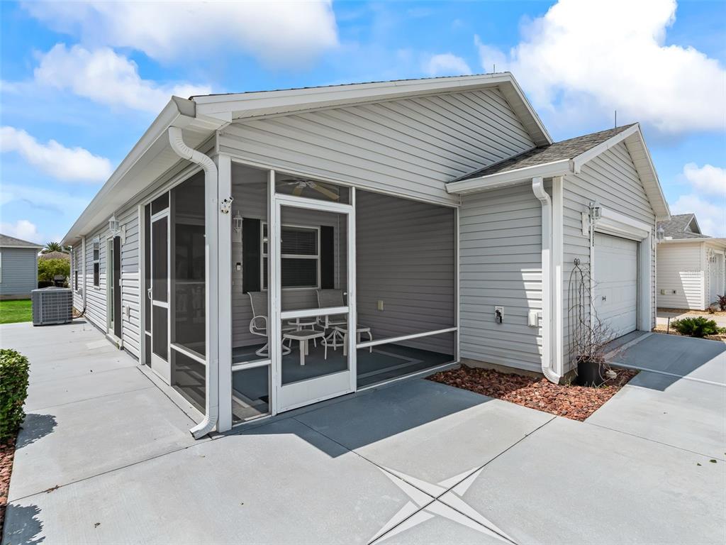 A view of a house exterior featuring a screened-in porch and a concrete patio — 1388 VIOLA COURT, THE VILLAGES, FL