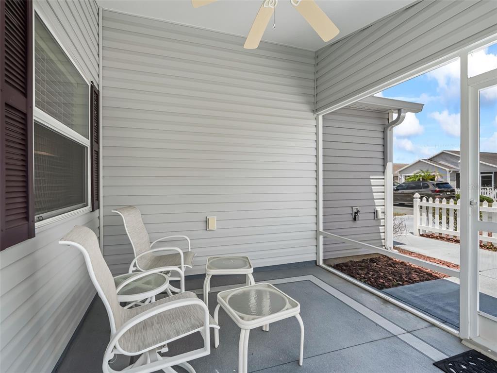 A screened-in porch features light gray siding, a ceiling fan, and two chairs with tables — 1388 VIOLA COURT, THE VILLAGES, FL
