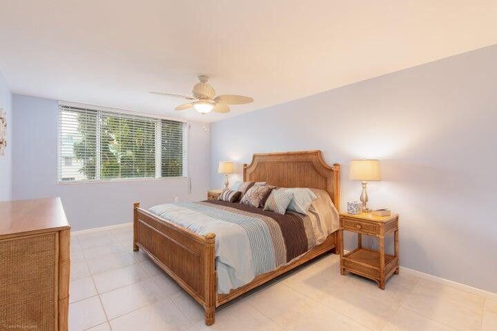 A bedroom features a wooden bed frame, two matching nightstands, and a ceiling fan — 110 Half Moon Circle # E2, Hypoluxo FL 33462, HYPOLUXO, FL