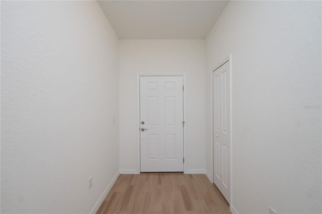 An entryway features light wood-look flooring, white walls, a white front door, and a closet — 4569 SAN LORENZO DRIVE, SEBRING, FL