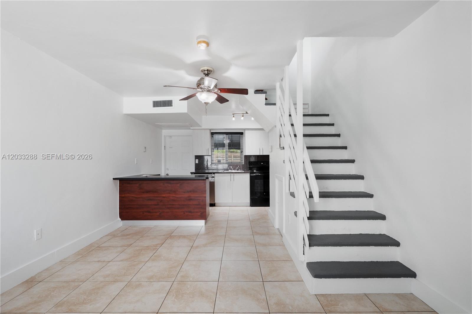 A kitchen with a breakfast bar and a staircase with dark treads in a room — 932 SW 6th St # 5, Miami FL 33130, MIAMI, FL