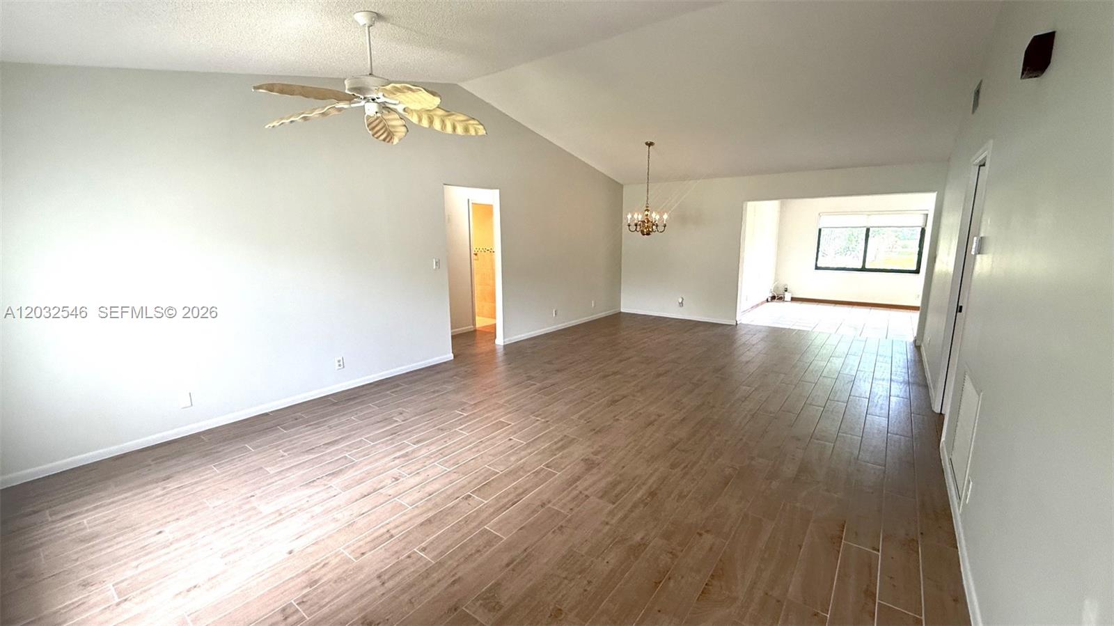 An empty living room features wood-look tile flooring, a vaulted ceiling, and a ceiling fan — 7905 Cloverfield Cir, Boca Raton FL 33433, BOCA RATON, FL