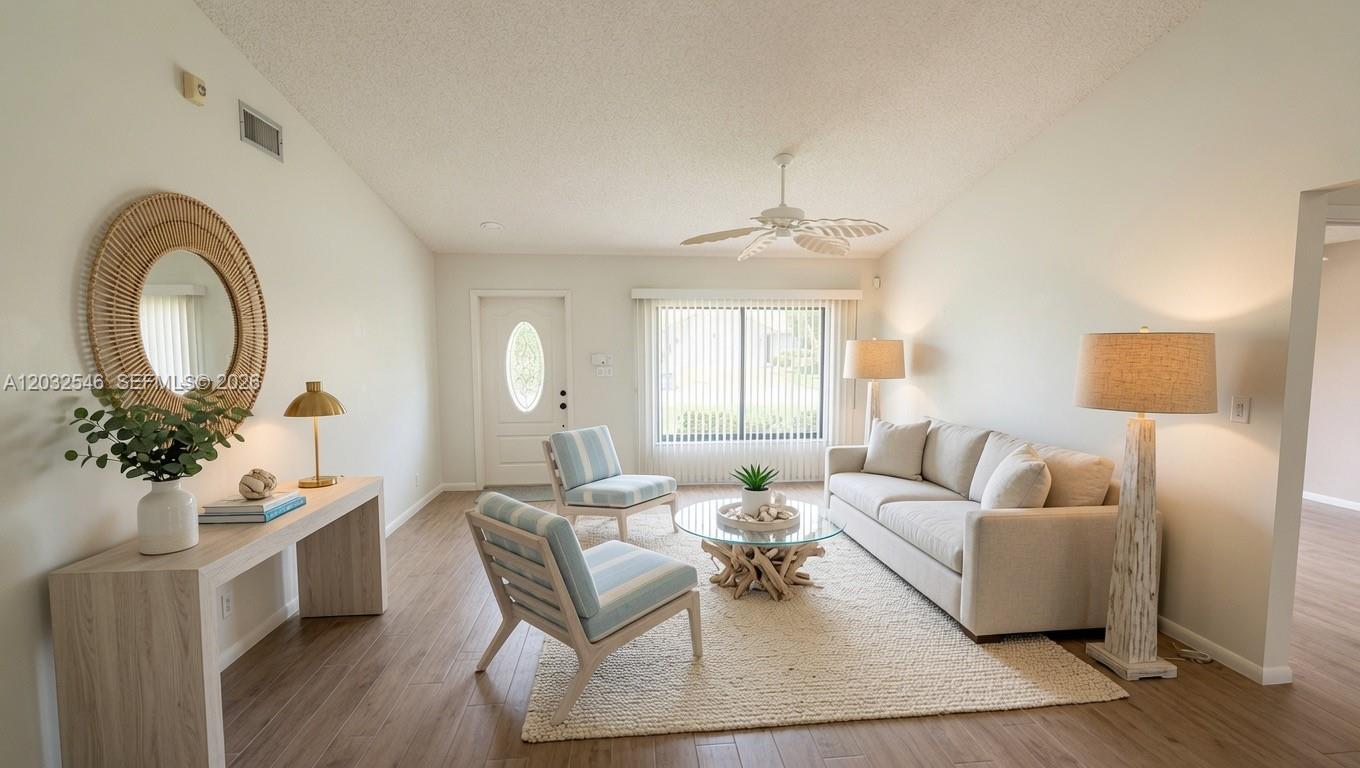 A bright, open-concept living and dining area features vaulted ceilings, light wood flooring, and coastal decor — 7905 Cloverfield Cir, Boca Raton FL 33433, BOCA RATON, FL