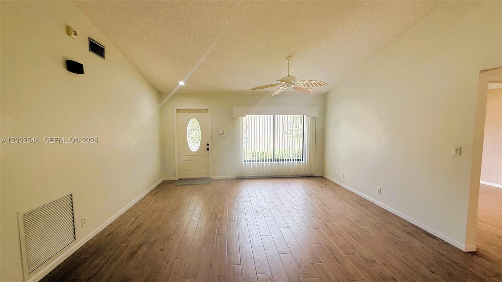 A spacious living room features vaulted ceilings, a palm-leaf ceiling fan, and wood-look tile flooring — 7905 Cloverfield Cir, Boca Raton FL 33433, BOCA RATON, FL