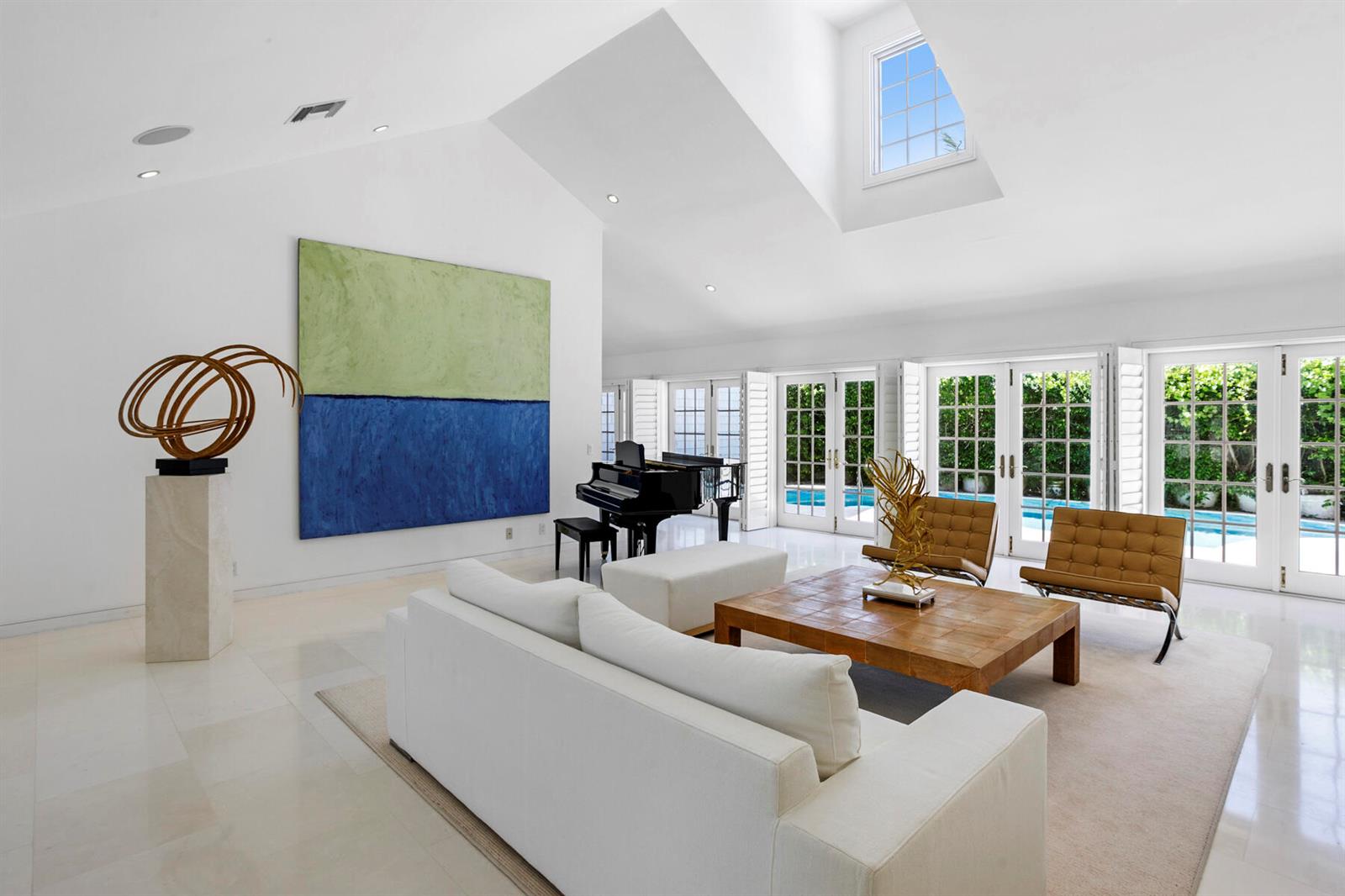A bright living room features a white sofa, grand piano, large abstract painting, and pool view — 222 Monterey Road, Palm Beach FL 33480, PALM BEACH, FL