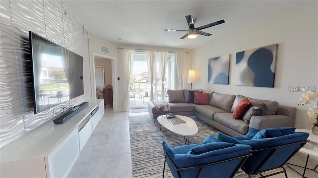 A living room features a sectional sofa, two blue armchairs, and a wall-mounted television — 3111 PARADOX CIRCLE UNIT 208, KISSIMMEE, FL