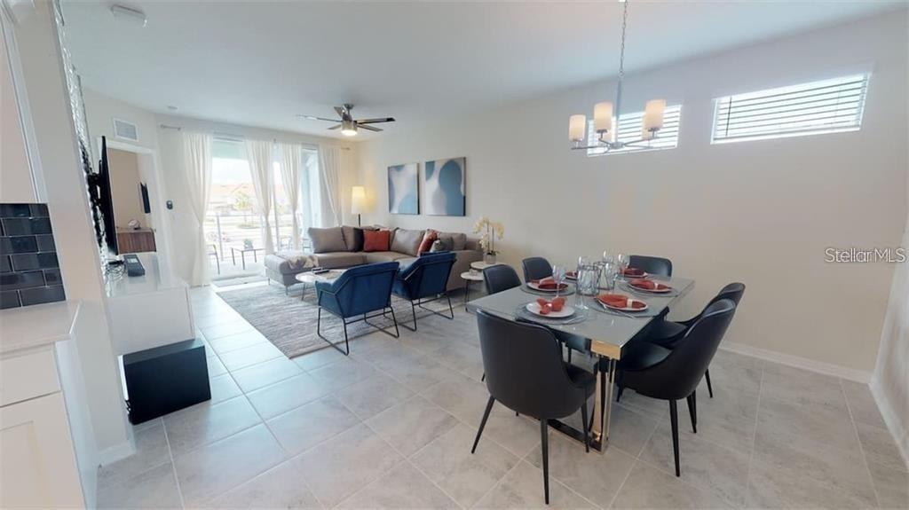 An open-concept living and dining area features tile flooring, a modern chandelier, and neutral walls — 3111 PARADOX CIRCLE UNIT 208, KISSIMMEE, FL