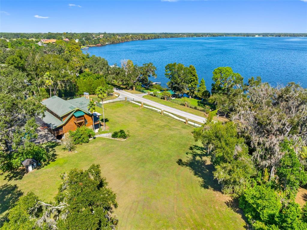 An aerial view shows a wooden house on a large grassy lot near a lake — 11401 THONOTOSASSA ROAD, THONOTOSASSA, FL