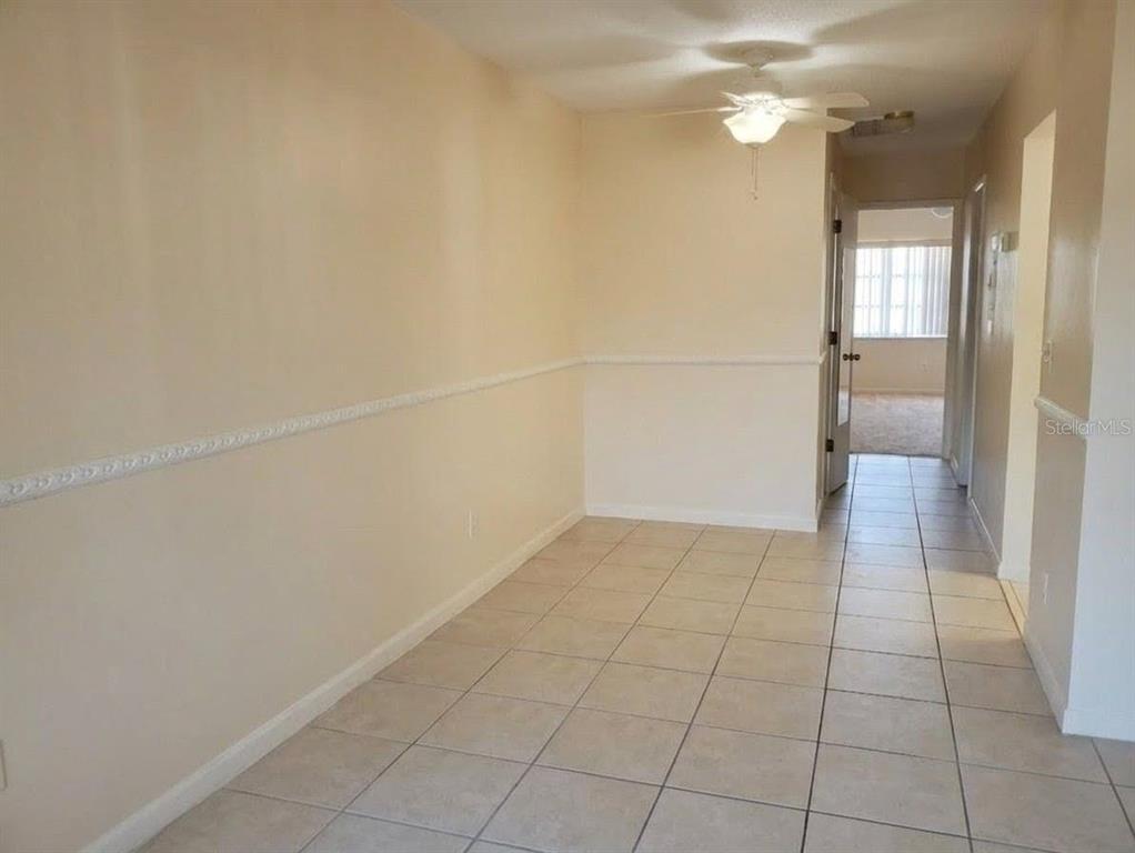A room with beige walls, chair rail molding, and light-colored tile flooring — 4744 AZALEA DRIVE UNIT 204, NEW PORT RICHEY, FL