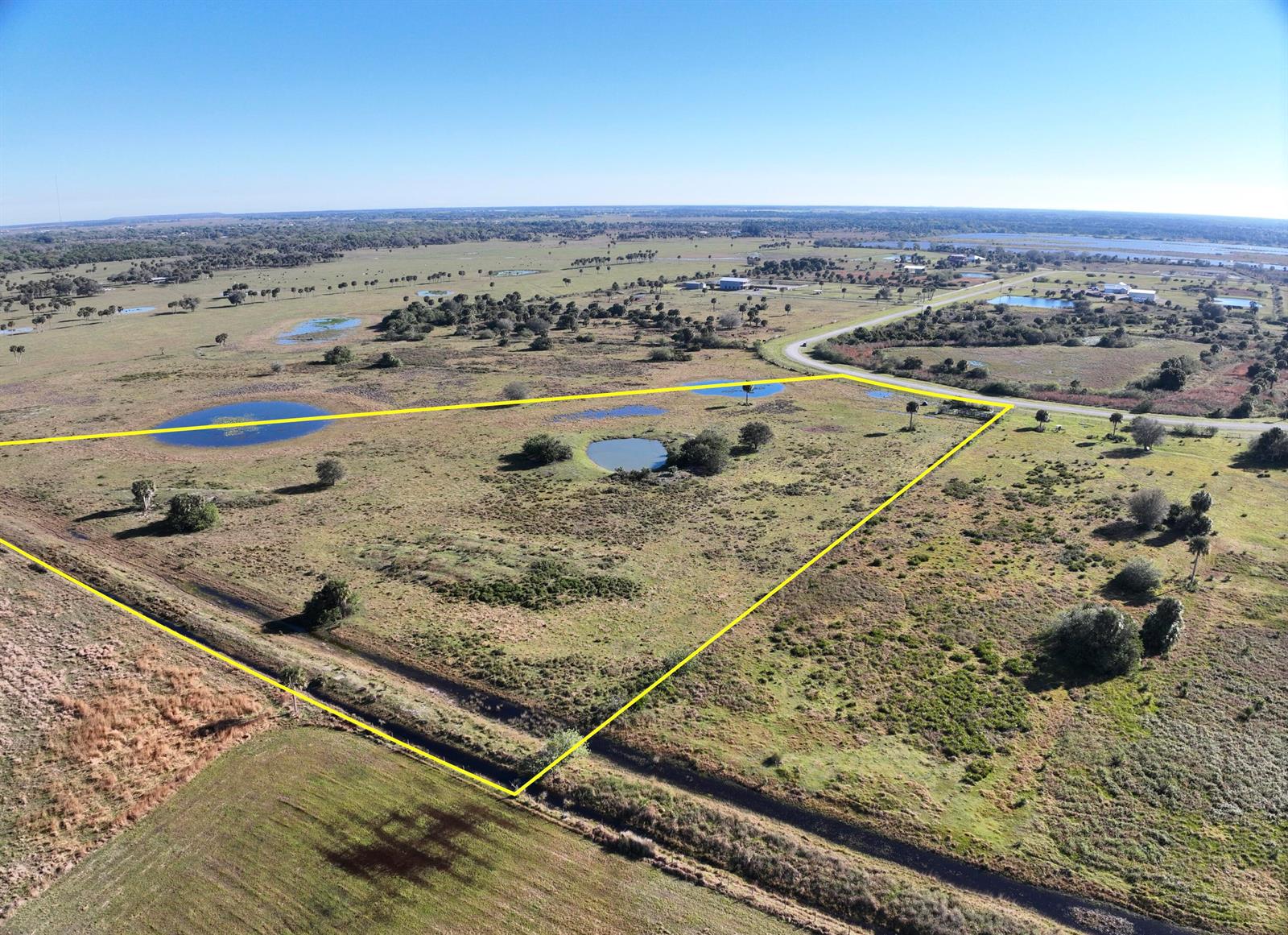 An aerial view shows a large, grassy, undeveloped plot of land outlined in yellow — 6584 SE 26th Trail, Okeechobee FL 34974, OKEECHOBEE, FL
