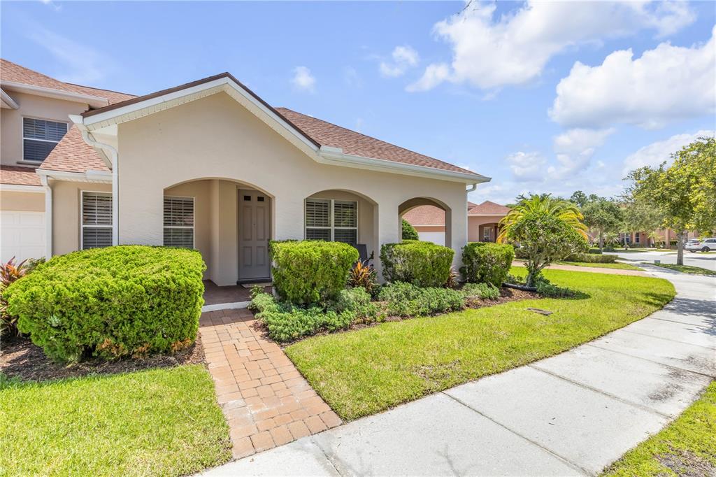 A tan stucco house with a brick walkway, arched entryway, and manicured landscaping — 3580 CASALTA CIRCLE, NEW SMYRNA BEACH, FL