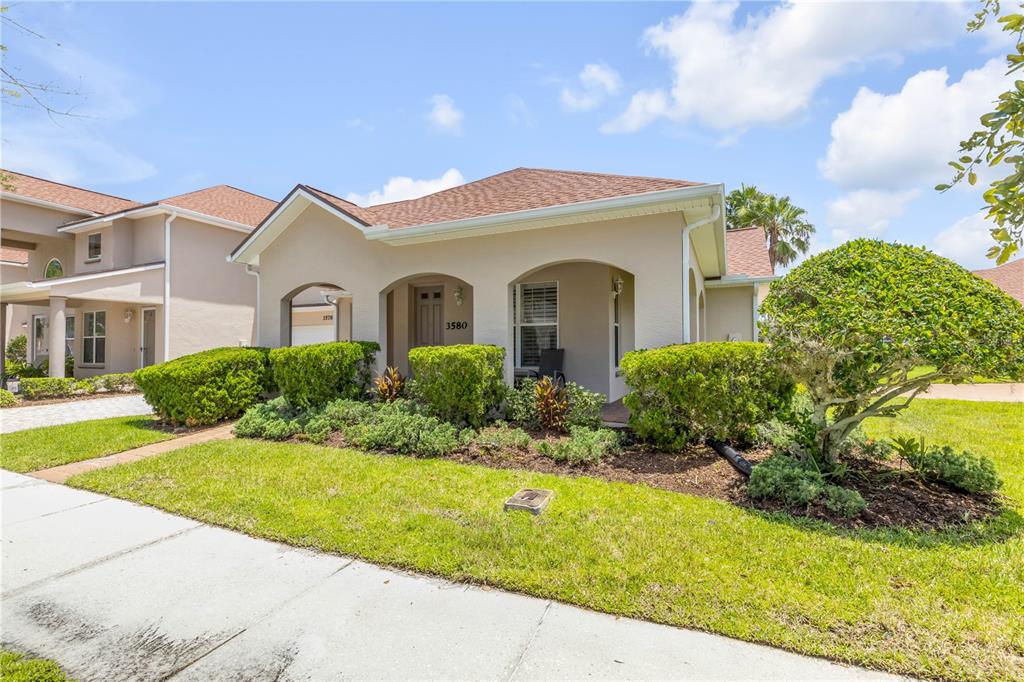 A single-story beige house with a covered entryway, arched openings, and landscaped front yard — 3580 CASALTA CIRCLE, NEW SMYRNA BEACH, FL