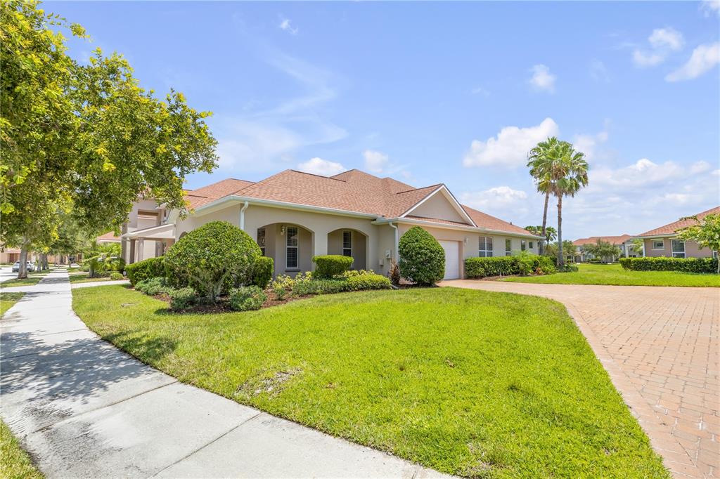 A single-story house with a tan exterior, a brown shingled roof, and a paved driveway — 3580 CASALTA CIRCLE, NEW SMYRNA BEACH, FL