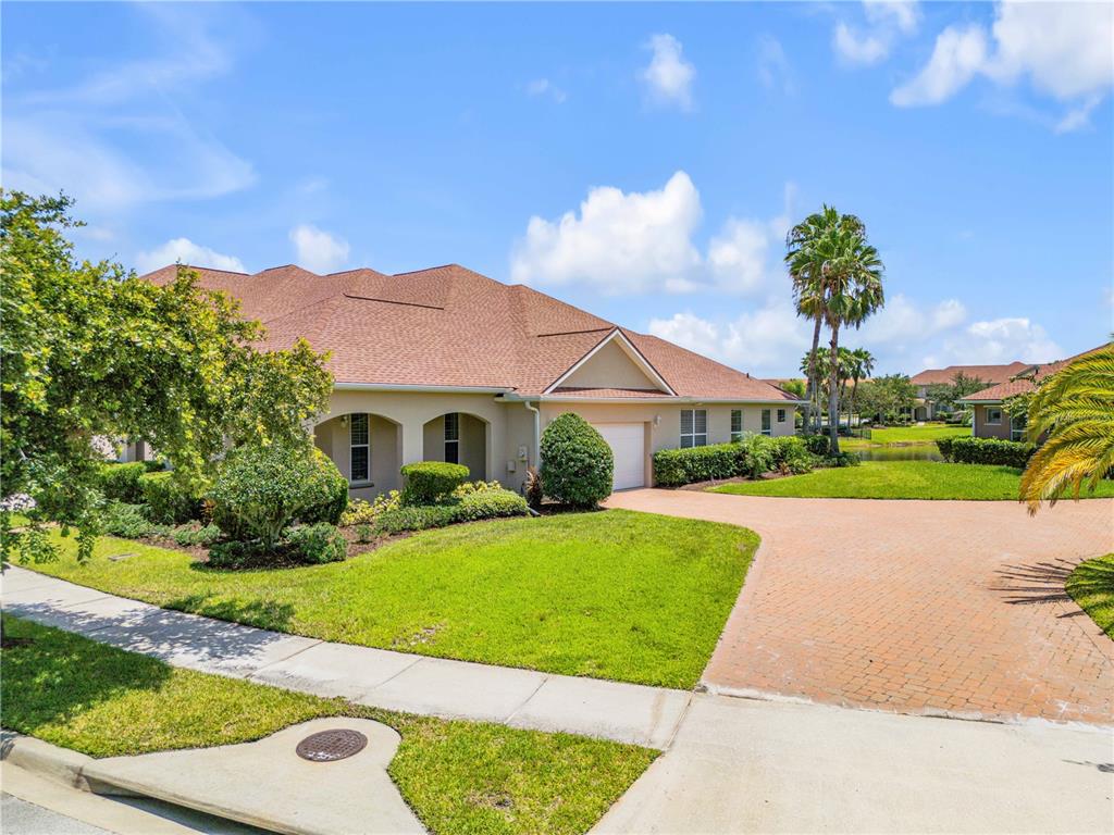 A single-story house with a brown shingled roof, beige stucco walls, and a brick driveway — 3580 CASALTA CIRCLE, NEW SMYRNA BEACH, FL