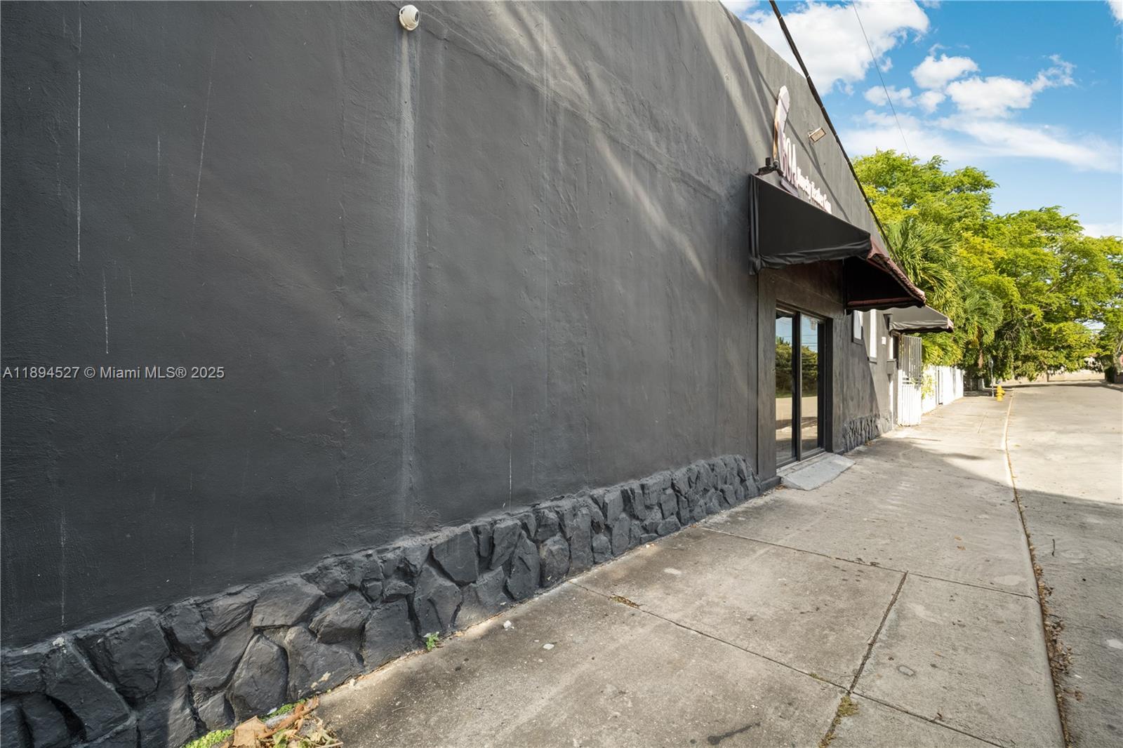 A dark gray exterior wall features a stone base and black fabric awnings — 2900 NW 11th Ave, Miami FL 33127, MIAMI, FL