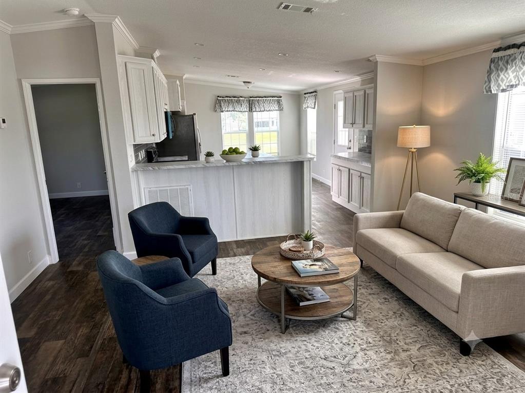 A living room with a beige sofa, two blue armchairs, and a kitchen island — 3428 GREENBLUFF ROAD UNIT 1135, ZELLWOOD, FL
