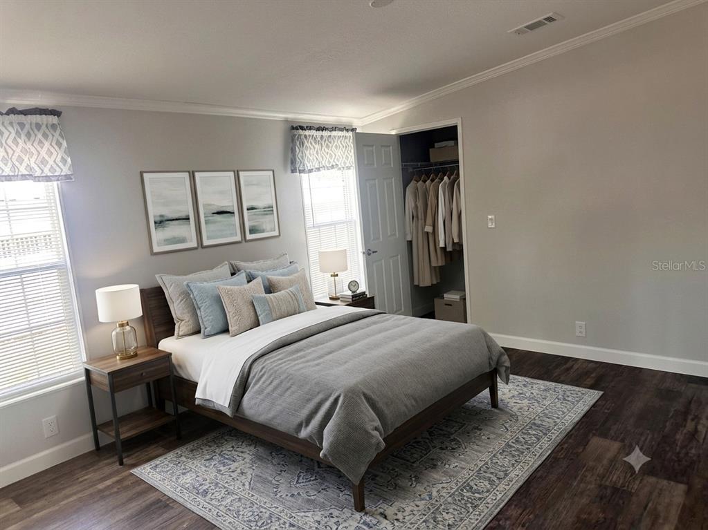 A bedroom features a bed with grey bedding, a patterned rug, and an open closet — 3428 GREENBLUFF ROAD UNIT 1135, ZELLWOOD, FL