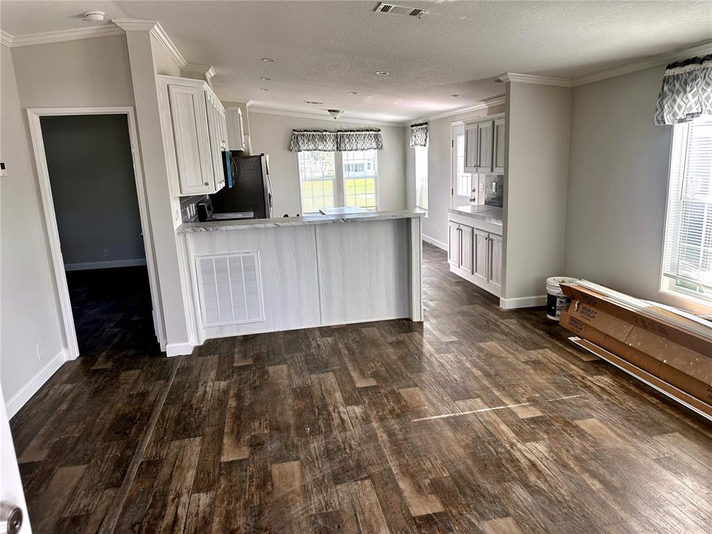 A kitchen and dining area with white cabinets, a breakfast bar, and wood-look flooring — 3428 GREENBLUFF ROAD UNIT 1135, ZELLWOOD, FL