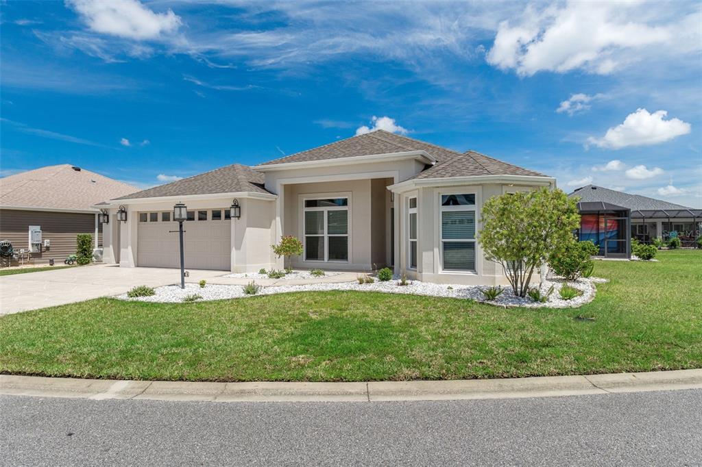 A single-story beige house with a two-car garage and a landscaped front yard — 3037 LICCIARDELLO PATH, THE VILLAGES, FL