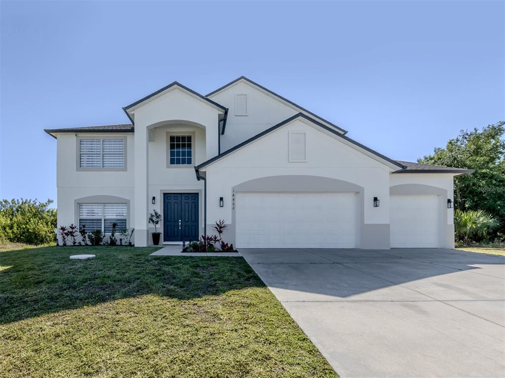A two-story house with white stucco siding, a three-car garage, and a concrete driveway — 14462 FORT WORTH CIRCLE, PORT CHARLOTTE, FL