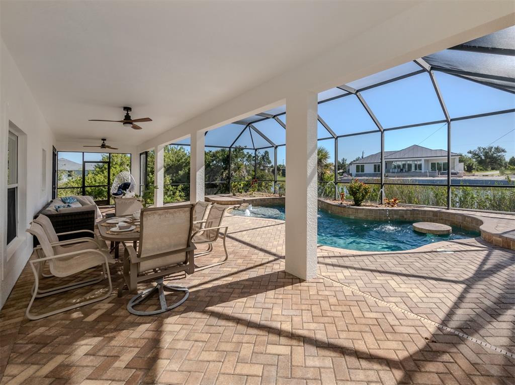 A covered patio features a dining set, lounge seating, and a screened-in pool with fountains — 14462 FORT WORTH CIRCLE, PORT CHARLOTTE, FL