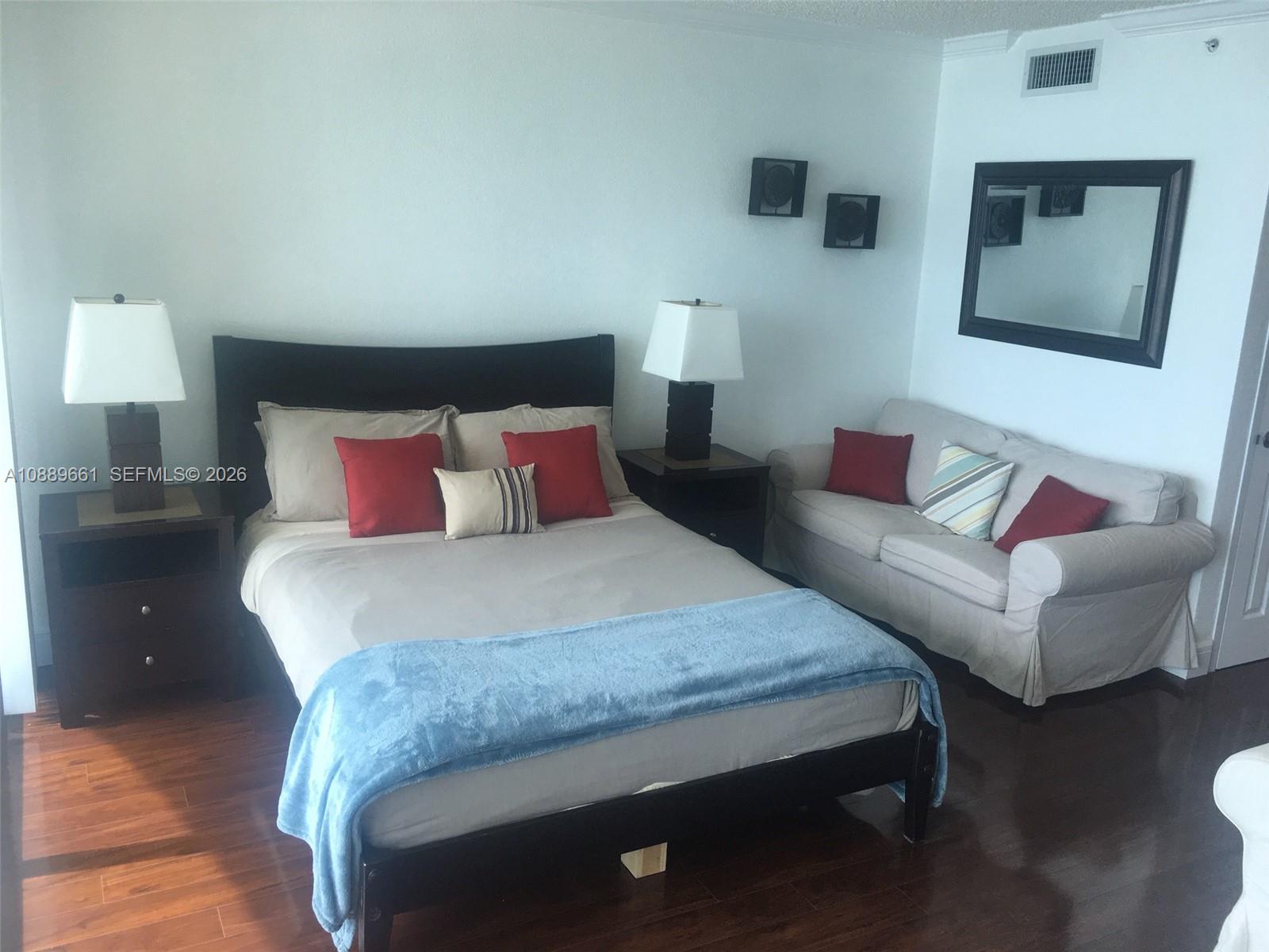 A bedroom features a dark wood bed, two nightstands, a beige sofa, and wood flooring — 2501 S OCEAN DR, Hollywood FL 33019, HOLLYWOOD, FL