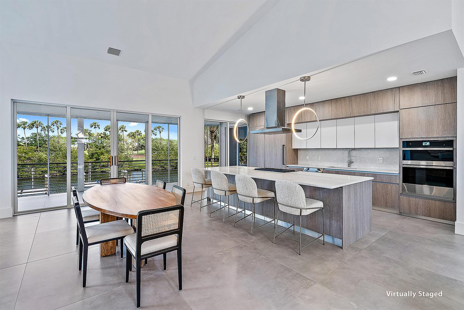 A modern kitchen and dining area features a large island, wood cabinetry, and glass doors — 802 Captains Way, Jupiter FL 33477, JUPITER, FL