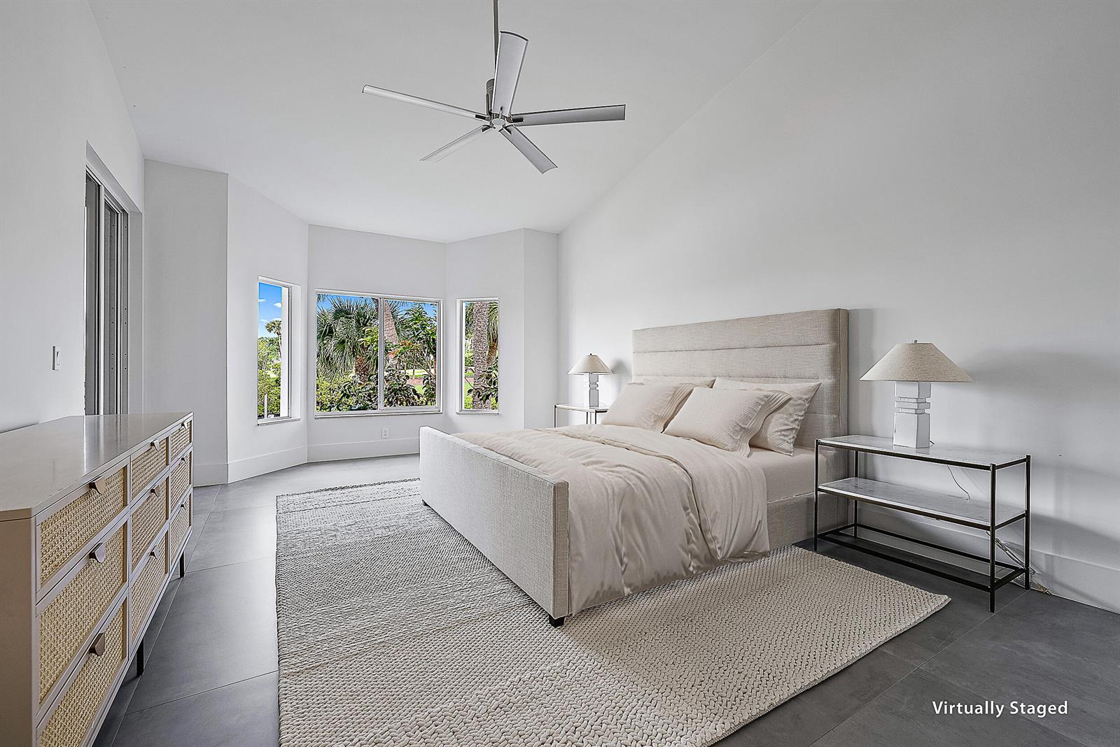 A bedroom features a bed, a dresser, and large windows with views of palm trees — 802 Captains Way, Jupiter FL 33477, JUPITER, FL
