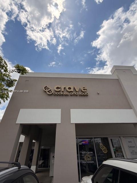 The exterior of a Crave Cookies and Soda storefront features a tan facade under a cloudy sky — 10730 NW 58 STREET, Doral FL 33178, DORAL, FL