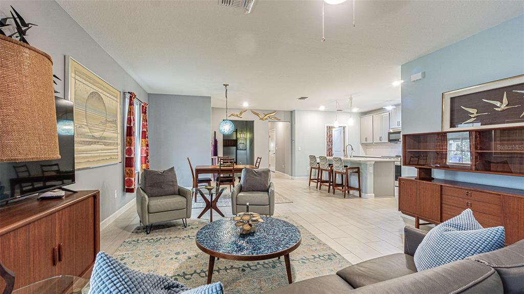 An open-concept living and dining area features tile flooring, neutral walls, and mid-century modern furniture — 31310 CABANA RYE AVENUE, SAN ANTONIO, FL