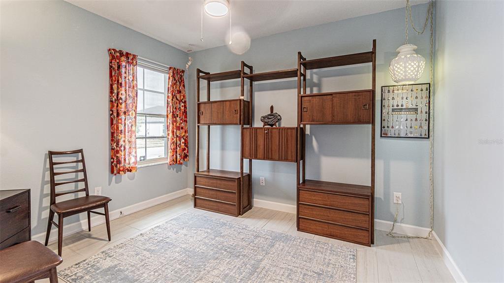 A room with light blue walls, a large wooden shelving unit, and a patterned rug — 31310 CABANA RYE AVENUE, SAN ANTONIO, FL